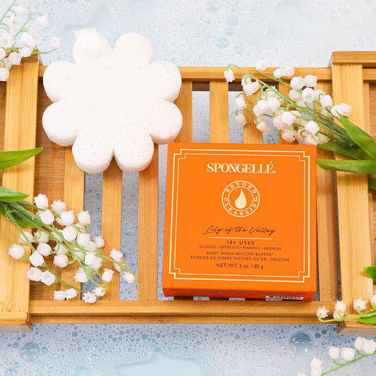 White flower-shaped body buffer beside orange SPONGELLE Lily of the Valley box