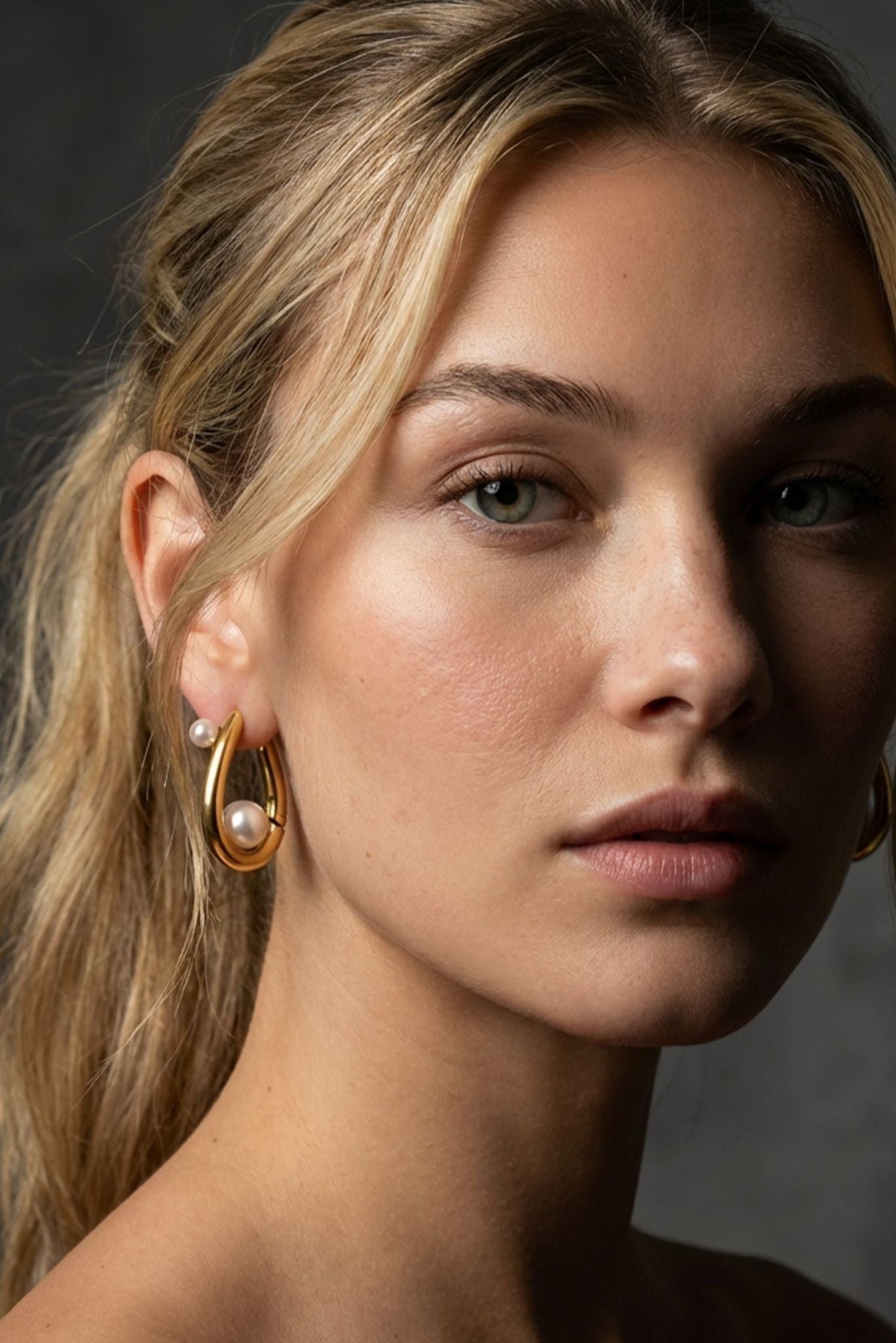 Gold-tone huggie hoop earrings with white pearl accents on side profile