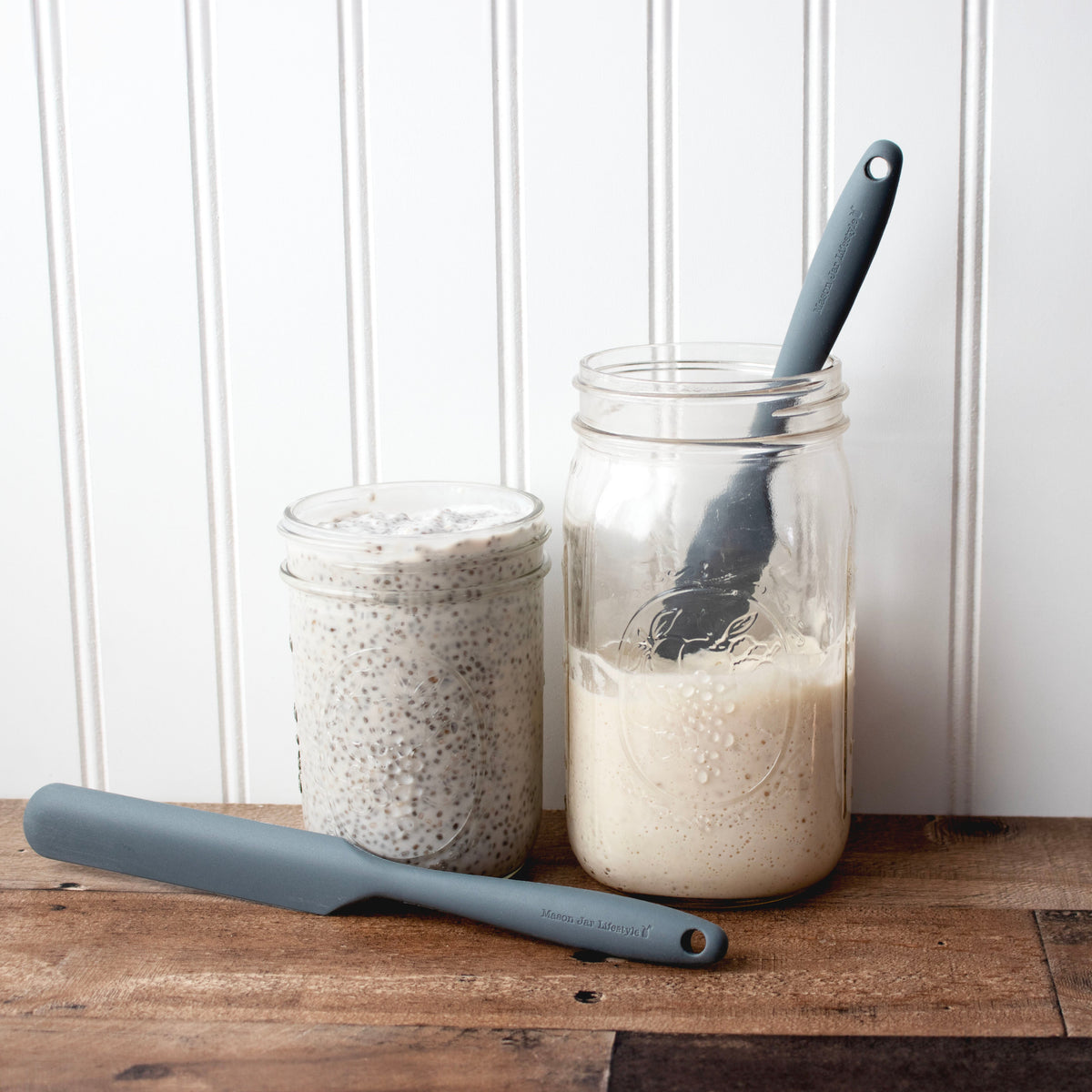 Gray silicone jar scraper lying beside cream-filled jars