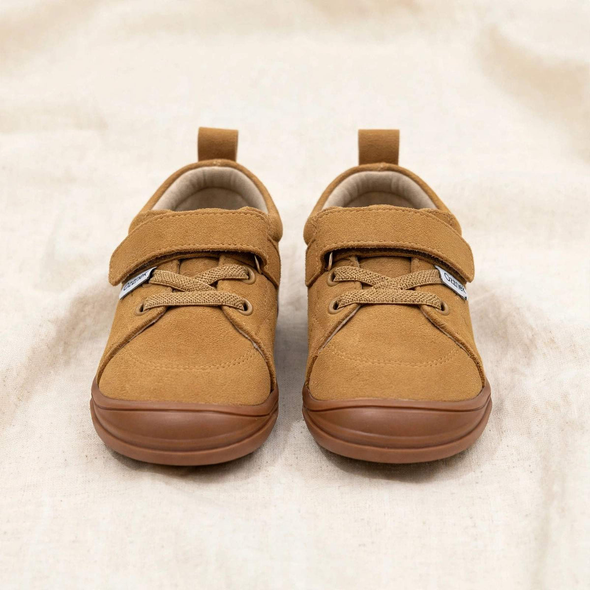Pair of tan suede kids' lace-up sneakers with low-profile rubber sole