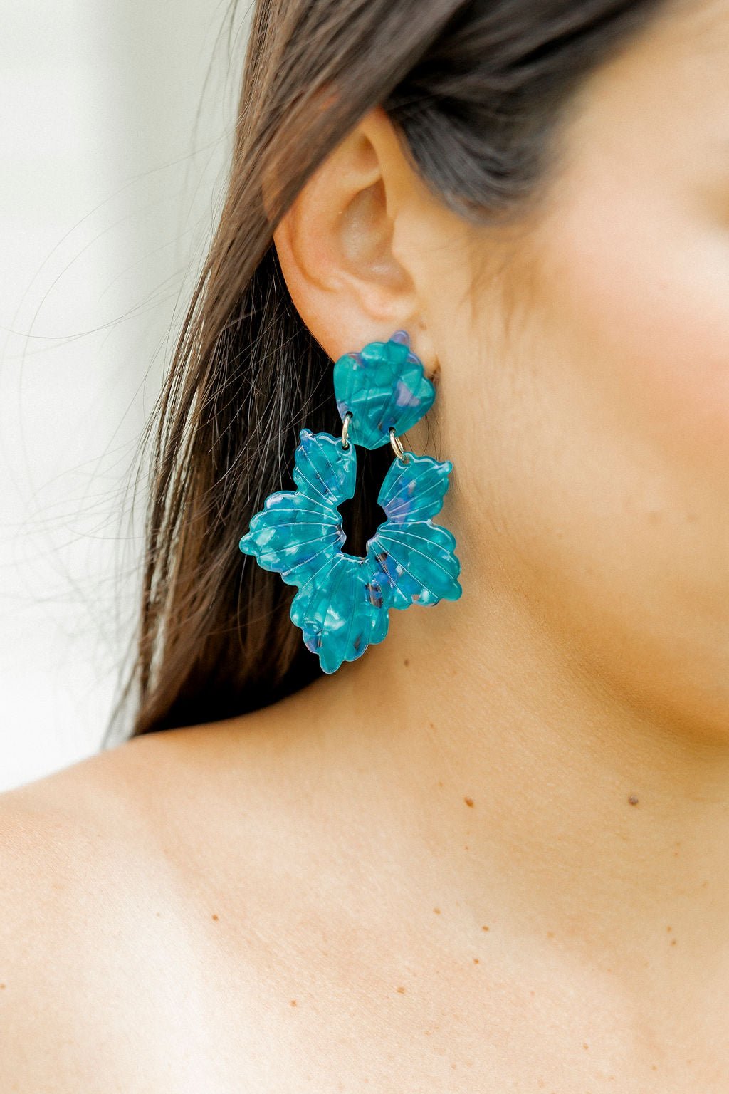Turquoise floral statement earrings with layered petals, close-up side profile