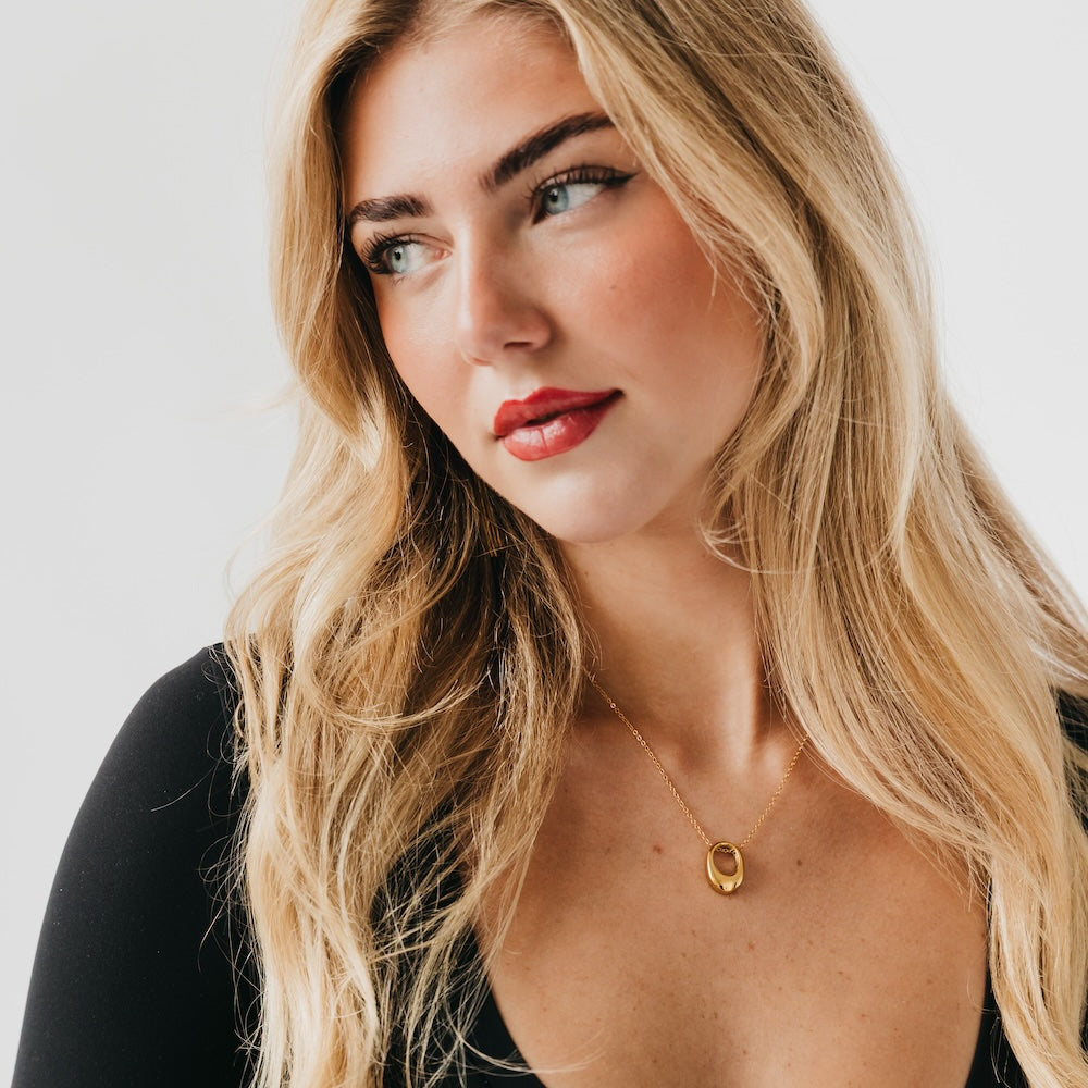 Gold mini open oval pendant necklace worn on black top