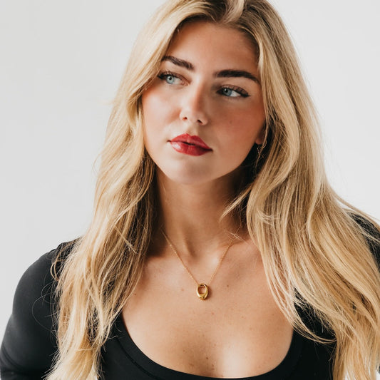 Gold mini open oval pendant necklace on model’s neckline, short chain