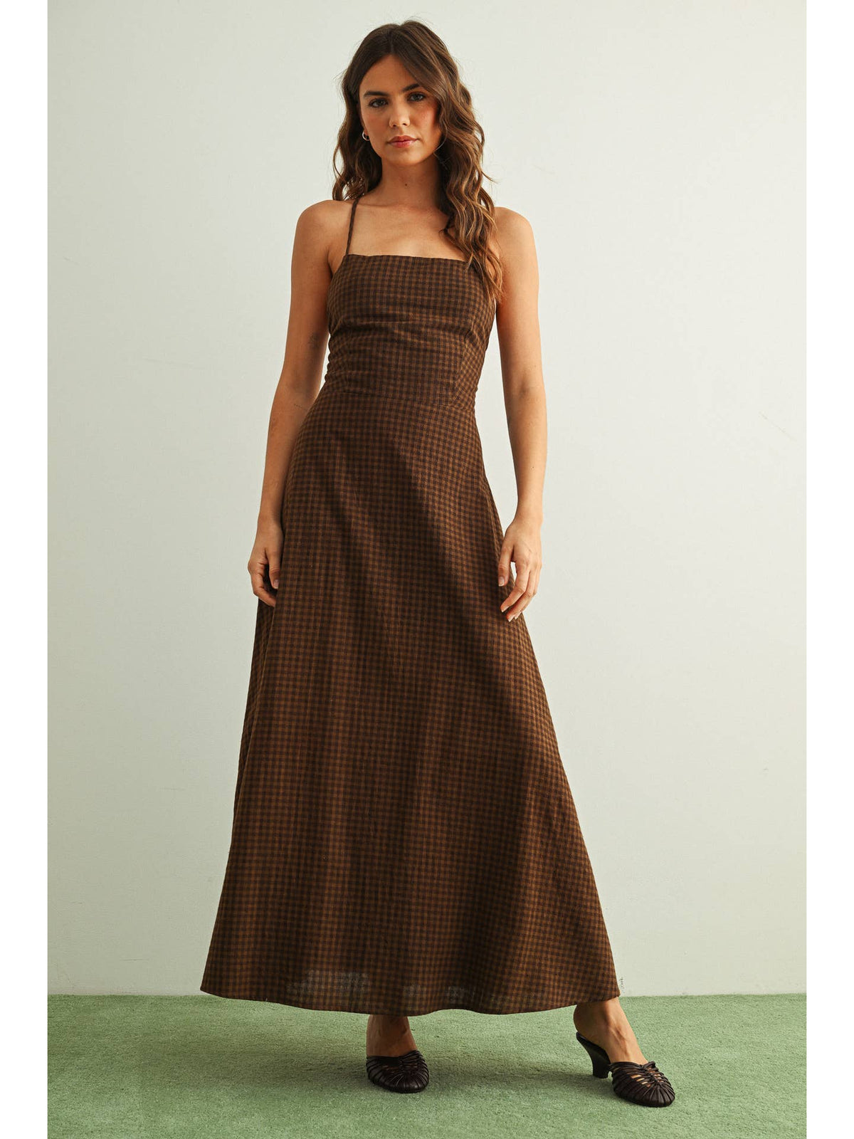 Chocolate gingham maxi dress with a fitted bodice, thin straps, and a flowing full-length skirt