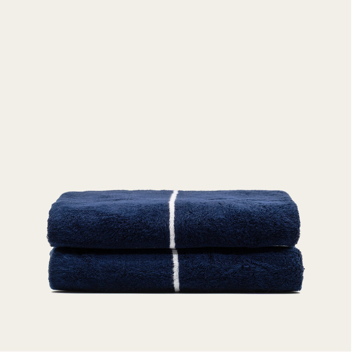 Navy cotton towels stack with white stripe accents, folded and layered.