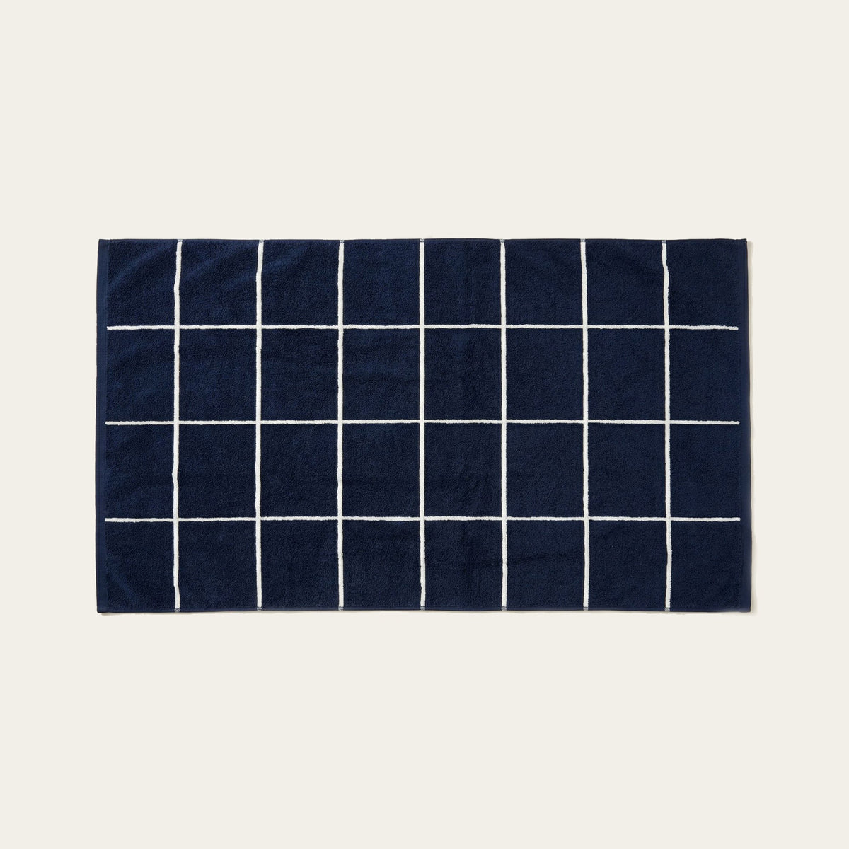Navy cotton towel with white grid lines pattern, flat and unfolded.