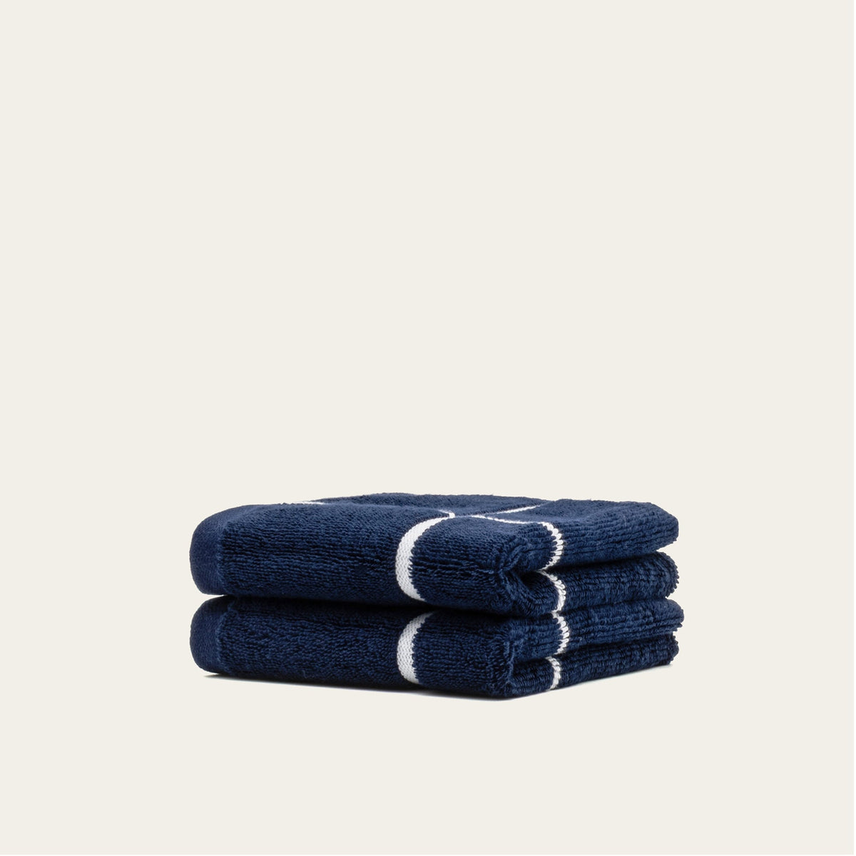 Navy cotton towel set folded with white stripe detail, neatly stacked.