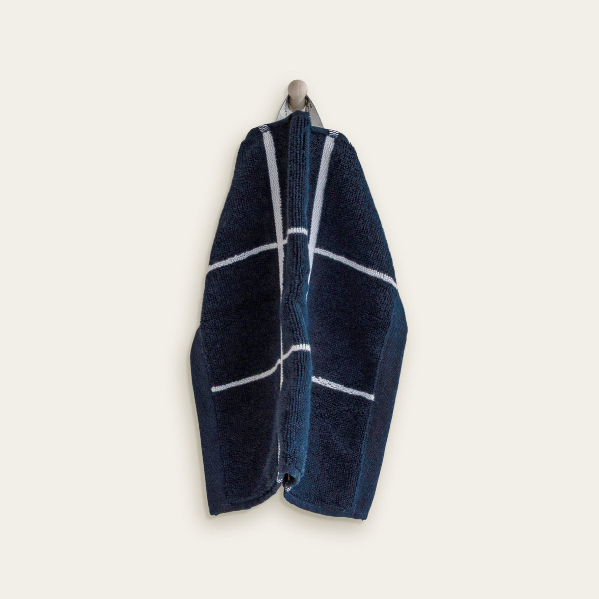 Navy cotton towel with white stripes and lines pattern, folded and draped.