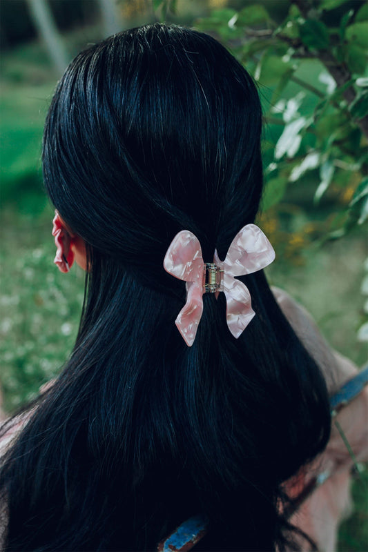 Pink bow hair claw clipped in dark hair