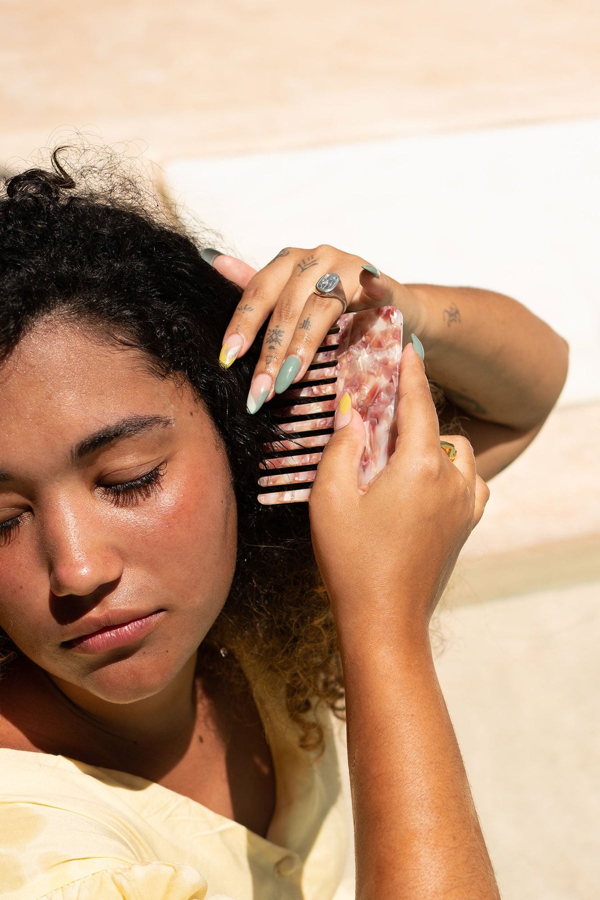 Rose marble-effect hair comb held near curly hair, wide teeth