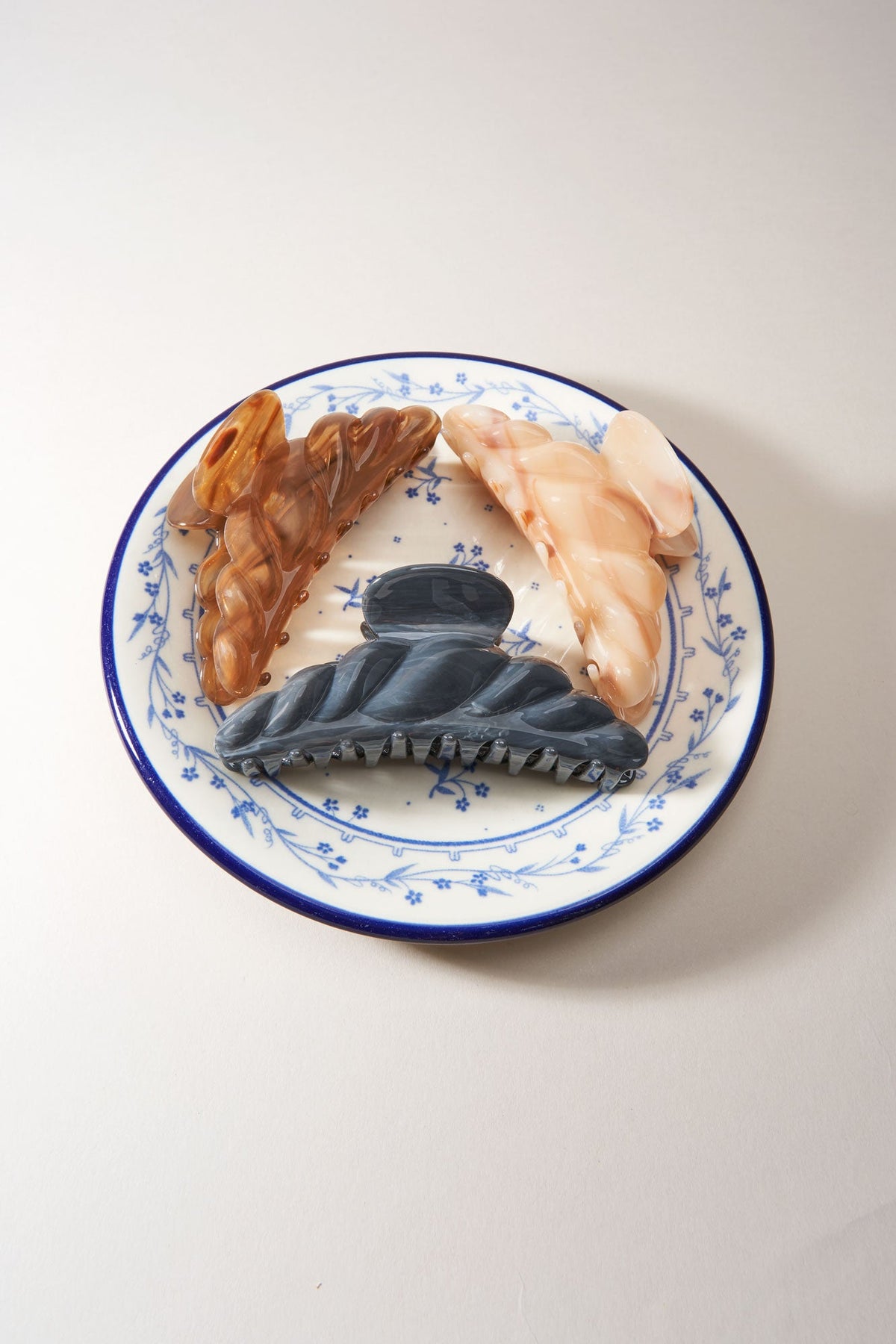 Croissant-shaped hair claw with golden and dark marbled stones on blue plate