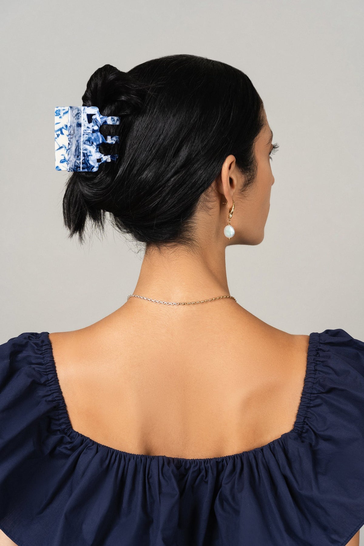 Blue-and-white patterned hair claw clipped in back bun on model