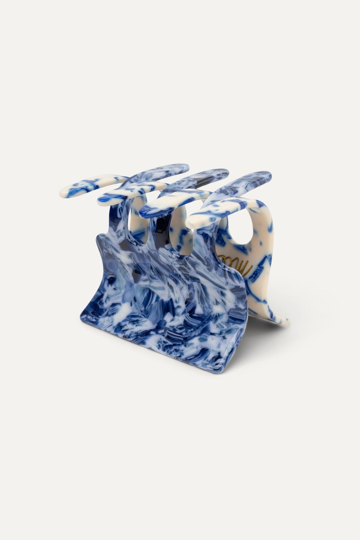 Delft blue and white hair claw, side view with curved grip prongs