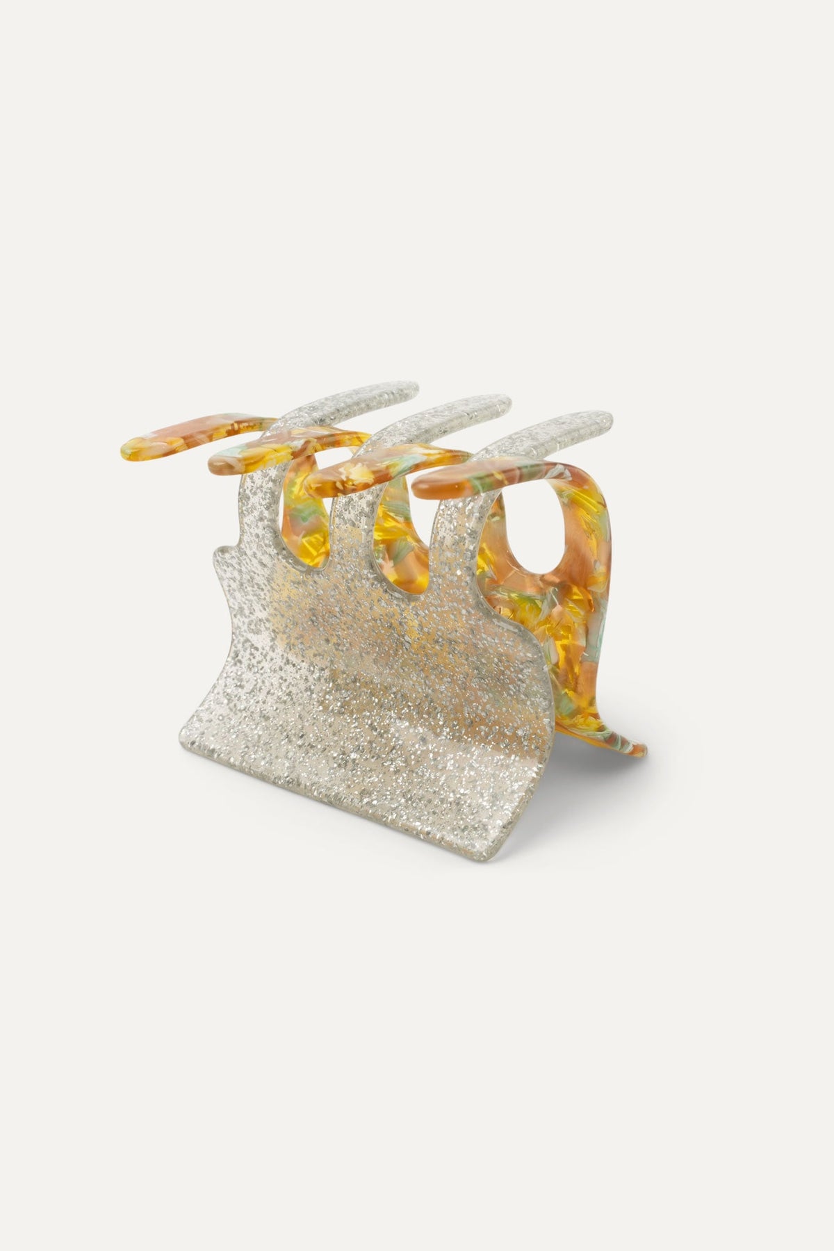 Decorative hair claw with glittery silver base and translucent amber resin cutout prongs