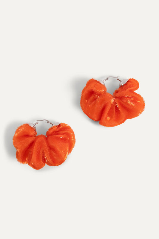 Pair of orange fabric scrunchie earrings with ruffled bow design and silver hooks
