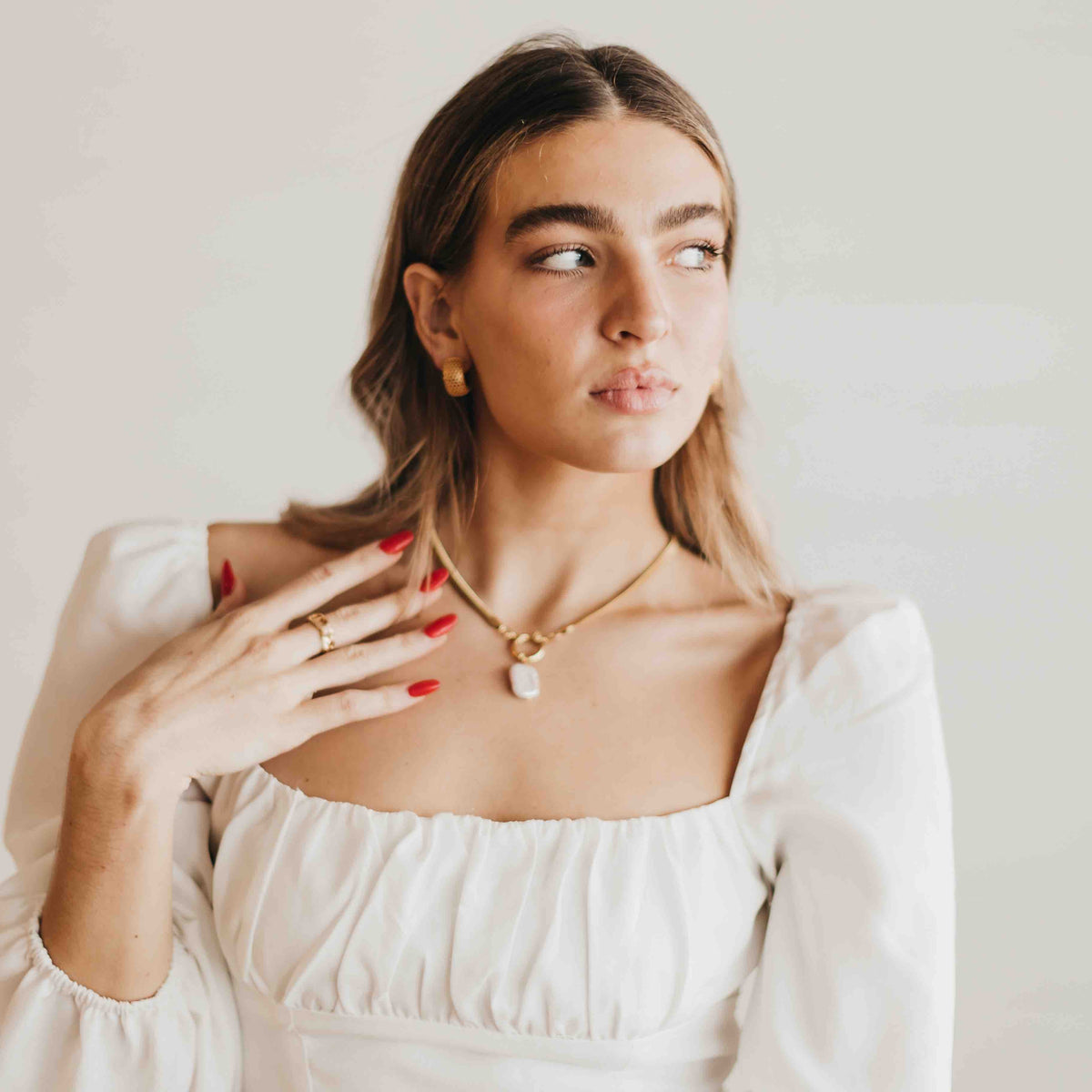 Gold-tone mother-of-pearl teardrop pendant necklace worn at collarbone