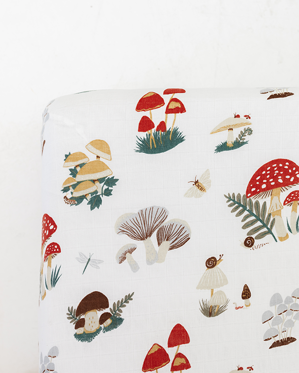 Fitted crib sheet with white base and colorful mushroom woodland print