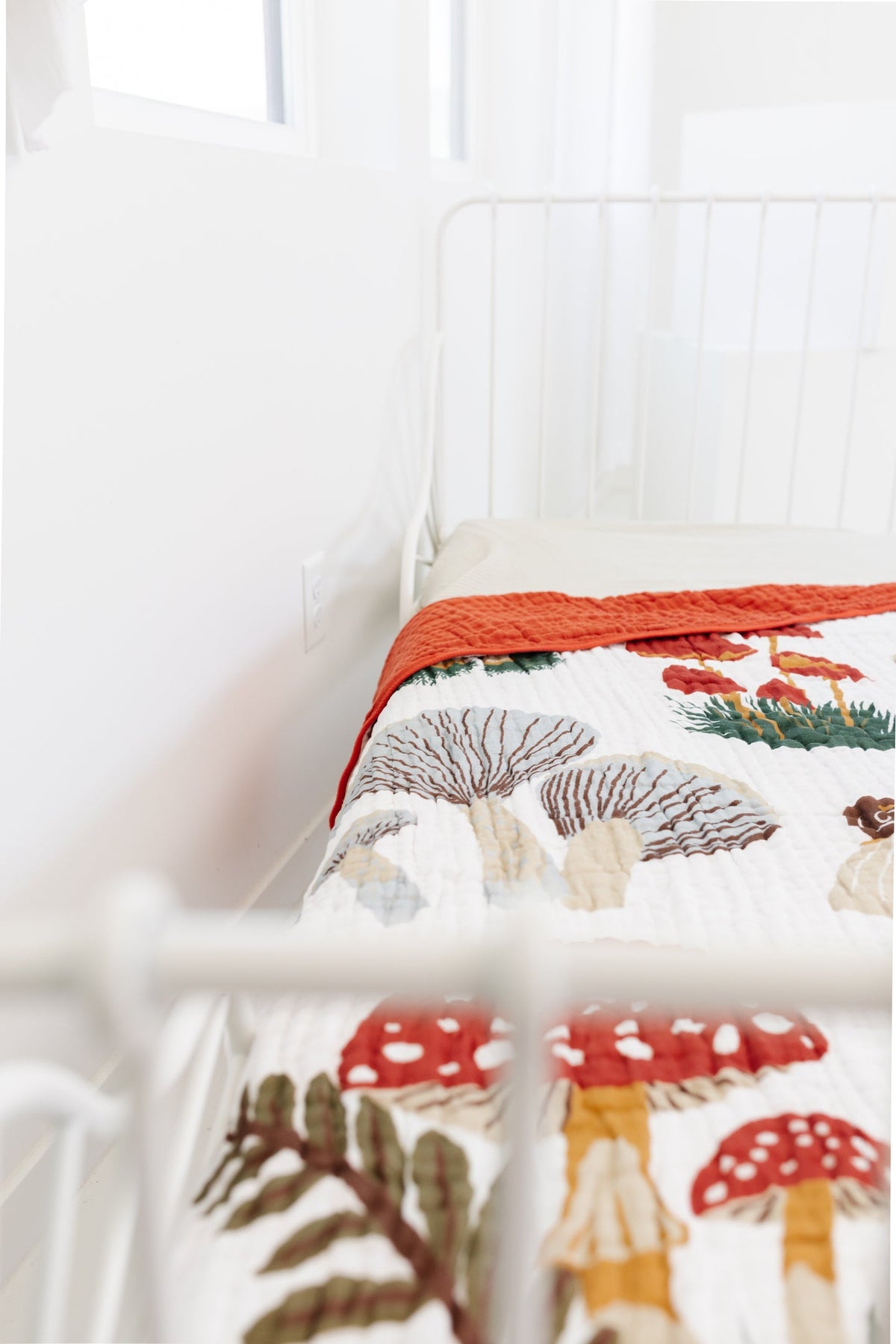 White throw blanket with orange edge and detailed mushroom pattern, close-up fold