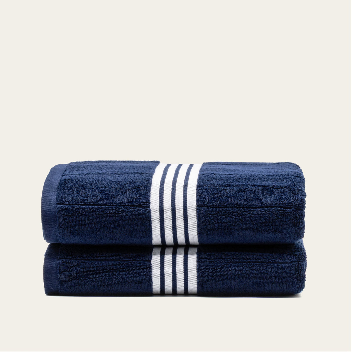 Navy cotton towel stack with white striped band, folded double towel.