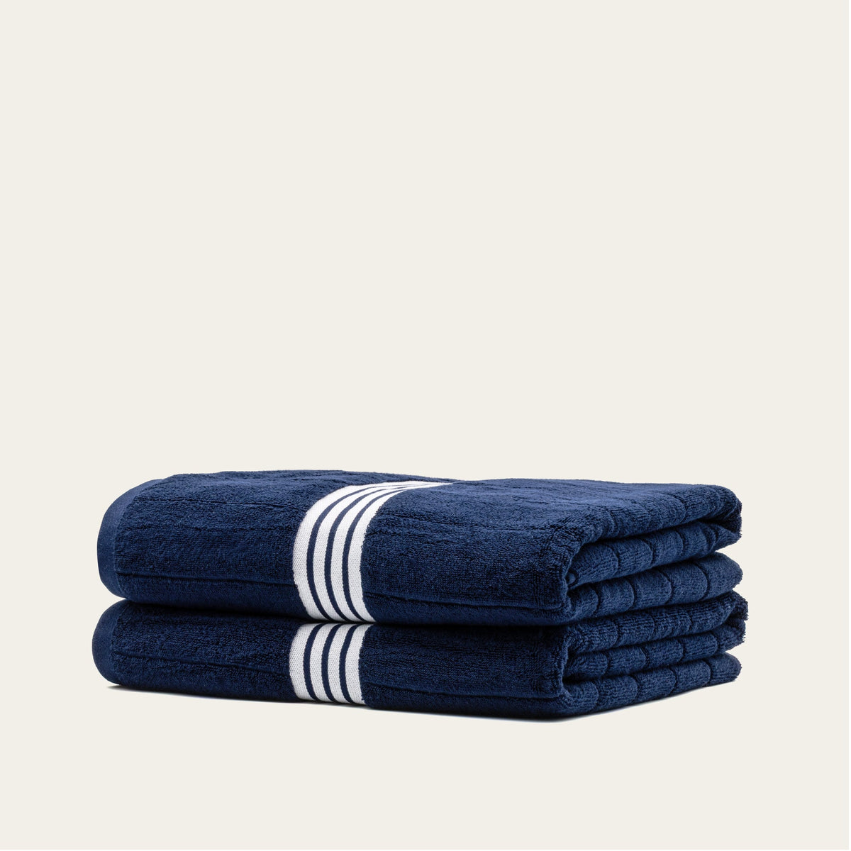 Navy cotton towel stack with white striped band, folded into a compact roll.