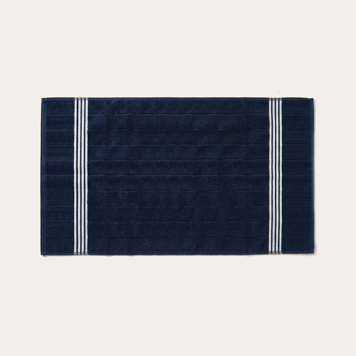 Nautilus navy cotton bath towel with two white vertical stripe borders, flat lay