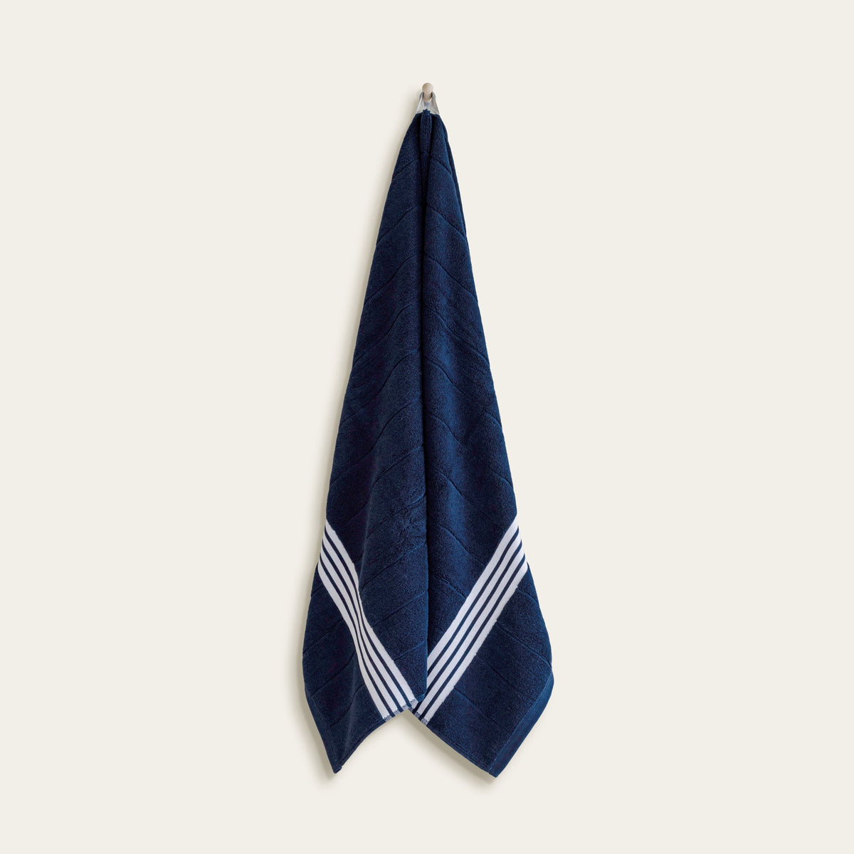 Nautilus Australian cotton towel hanging, navy with white striped border, angled view