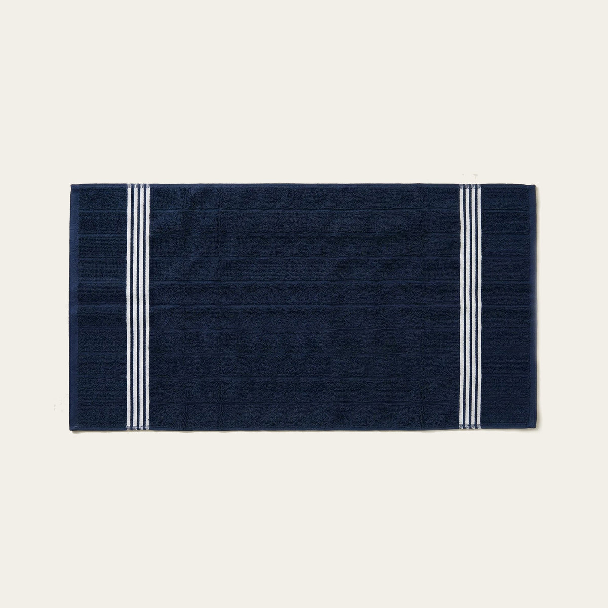 Nautilus navy cotton bath towel with two white vertical stripe borders, folded