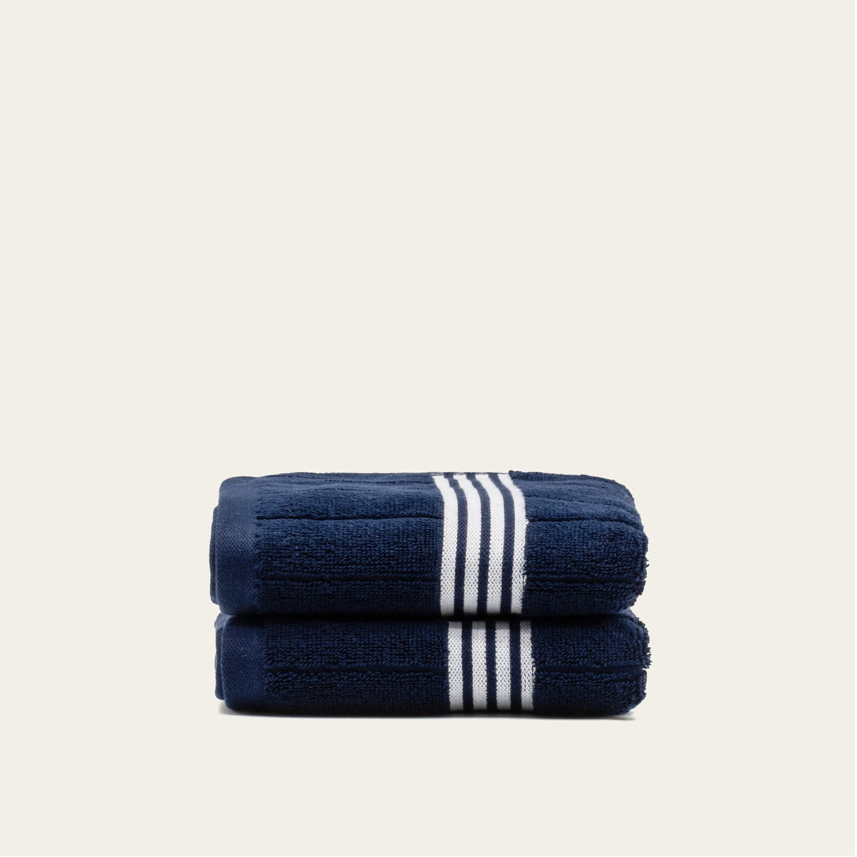 Navy cotton towel set with white striped bands, two towels folded with band centered.