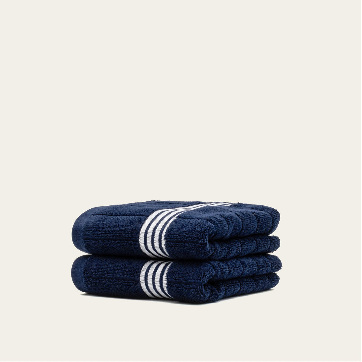 Navy cotton towels with white striped bands, folded stack with visible stripe detail.
