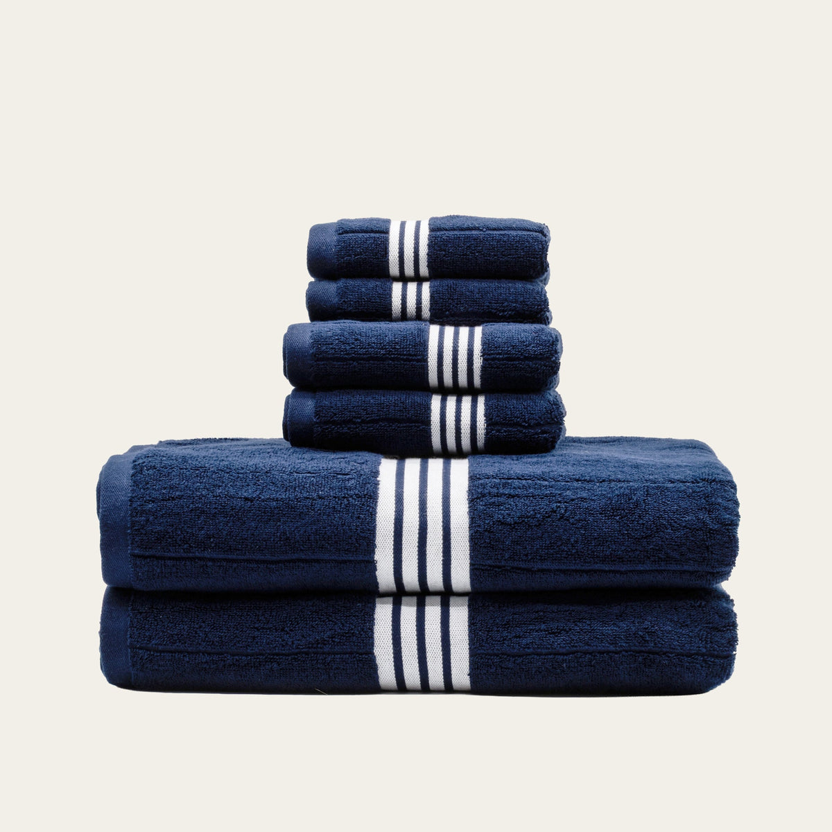 Navy cotton bath towels set with white striped bands, folded stack of three towels.