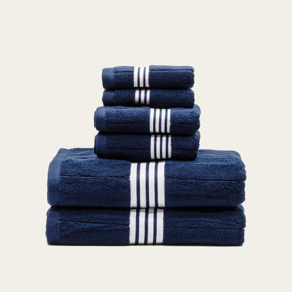 Two folded navy towels with white triple-stripe bands, top rolled