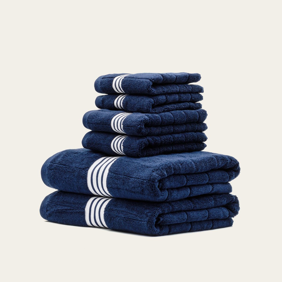 Tall stack of navy terry towels with white triple-stripe bands