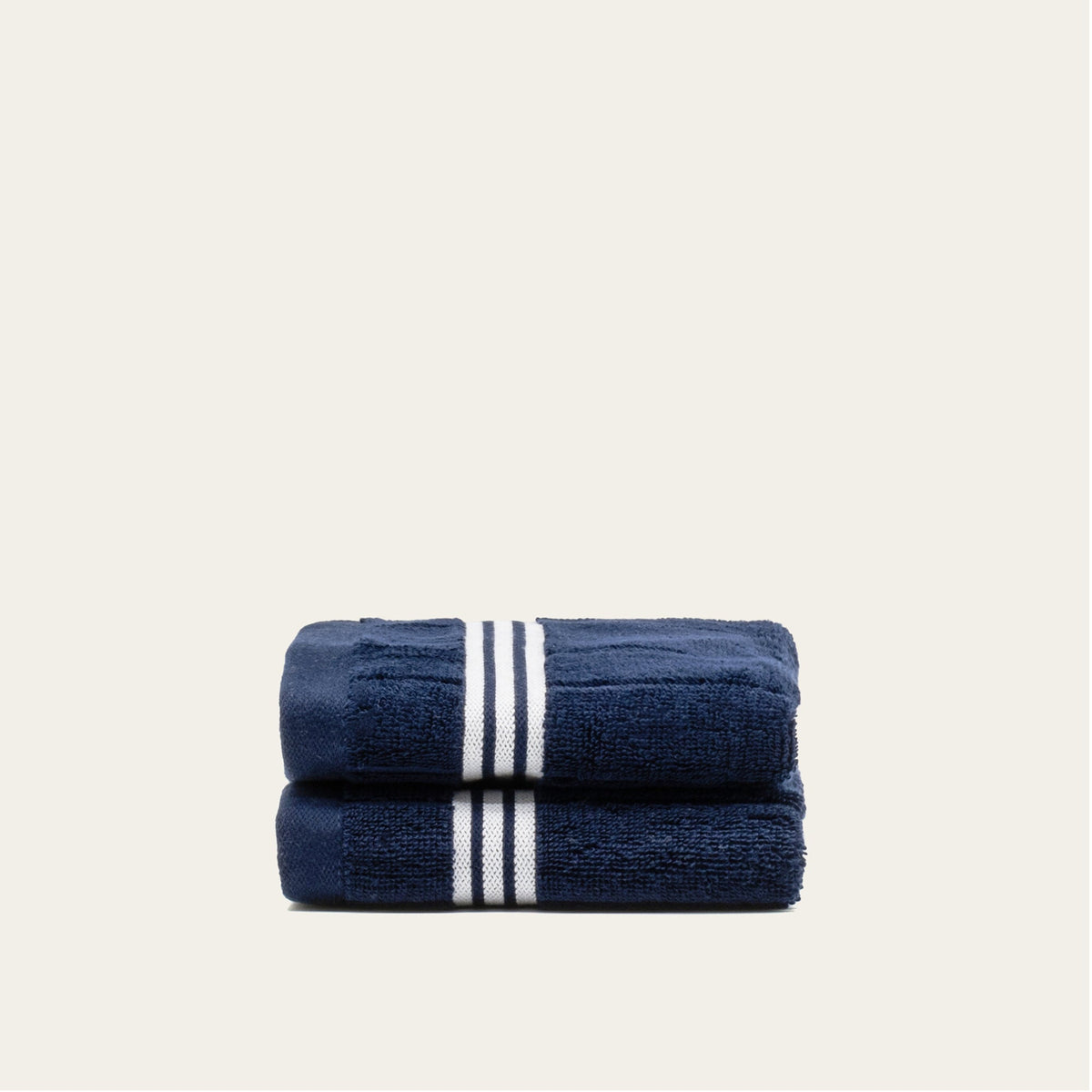 Nautilus navy cotton towels with two white stripe bands, folded stack