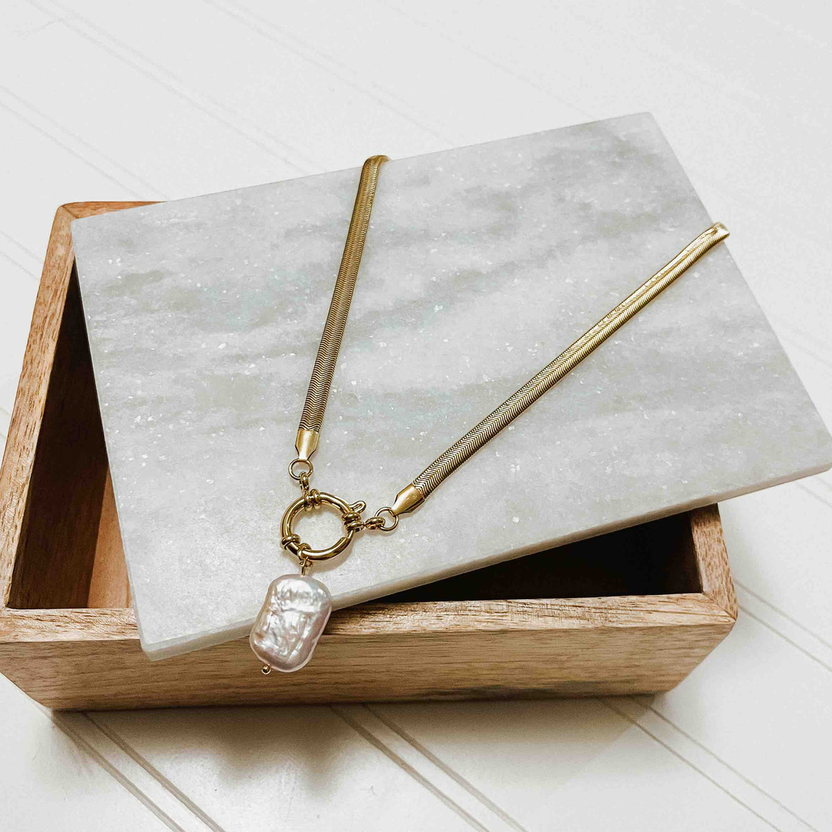 Gold-tone mother-of-pearl teardrop pendant necklace shown on a jewelry display
