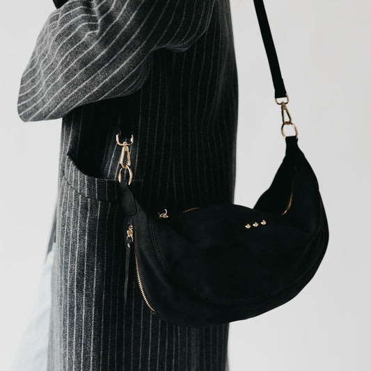Black nubuck crossbody bag with crescent shape and gold-tone hardware