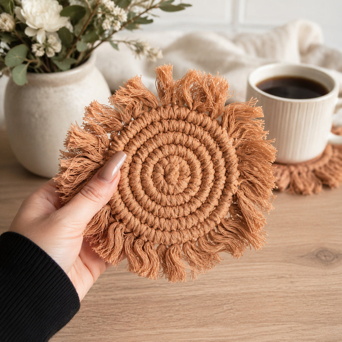 Caramel brown braided rope tassel coaster held in hand with circular braid and fringe