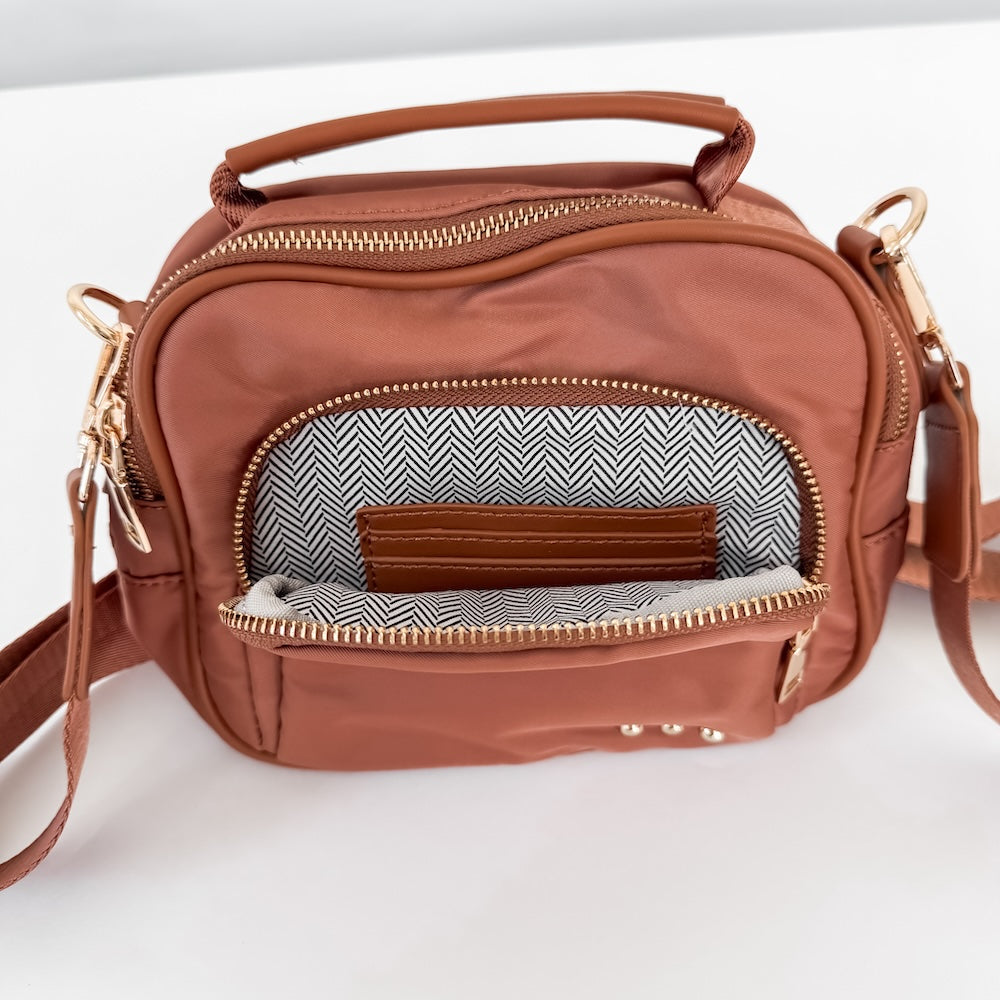 Brown nylon crossbody bag with front zip pocket and chevron-lined organizer