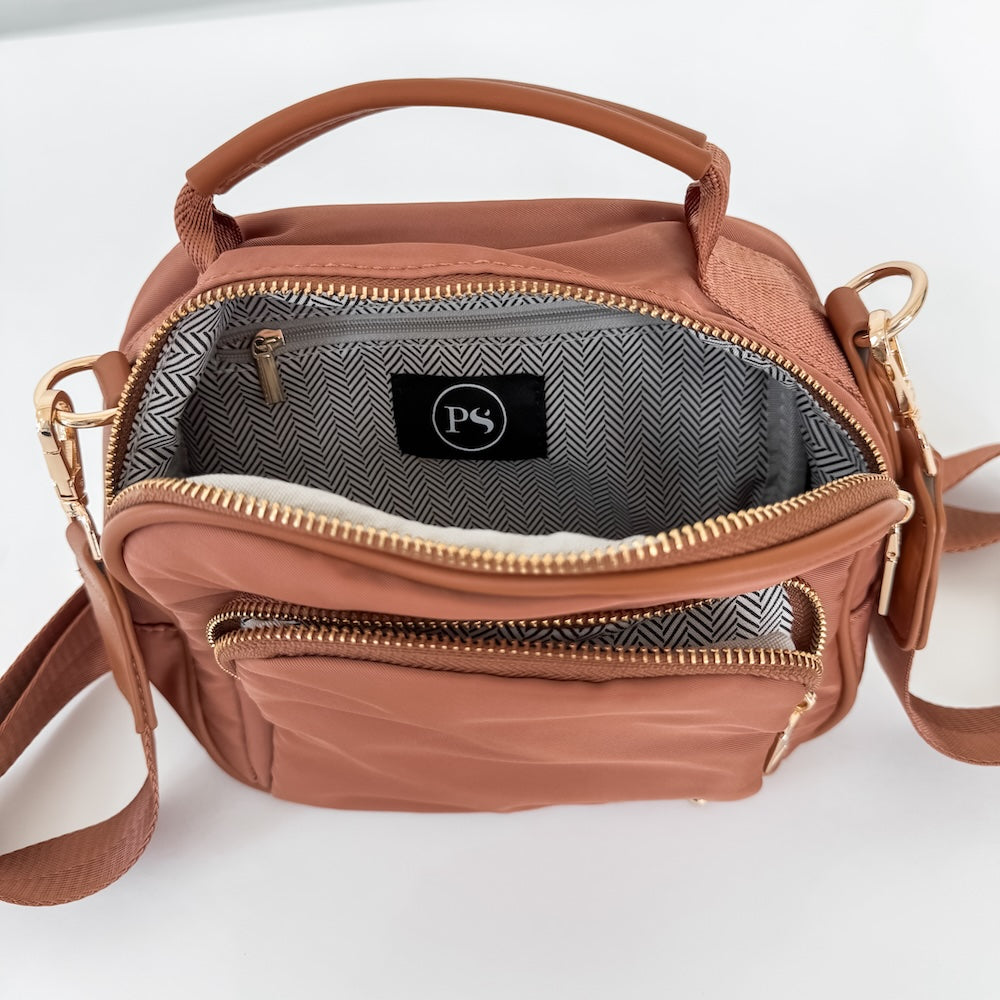 Brown nylon crossbody bag open with chevron interior and zip compartments