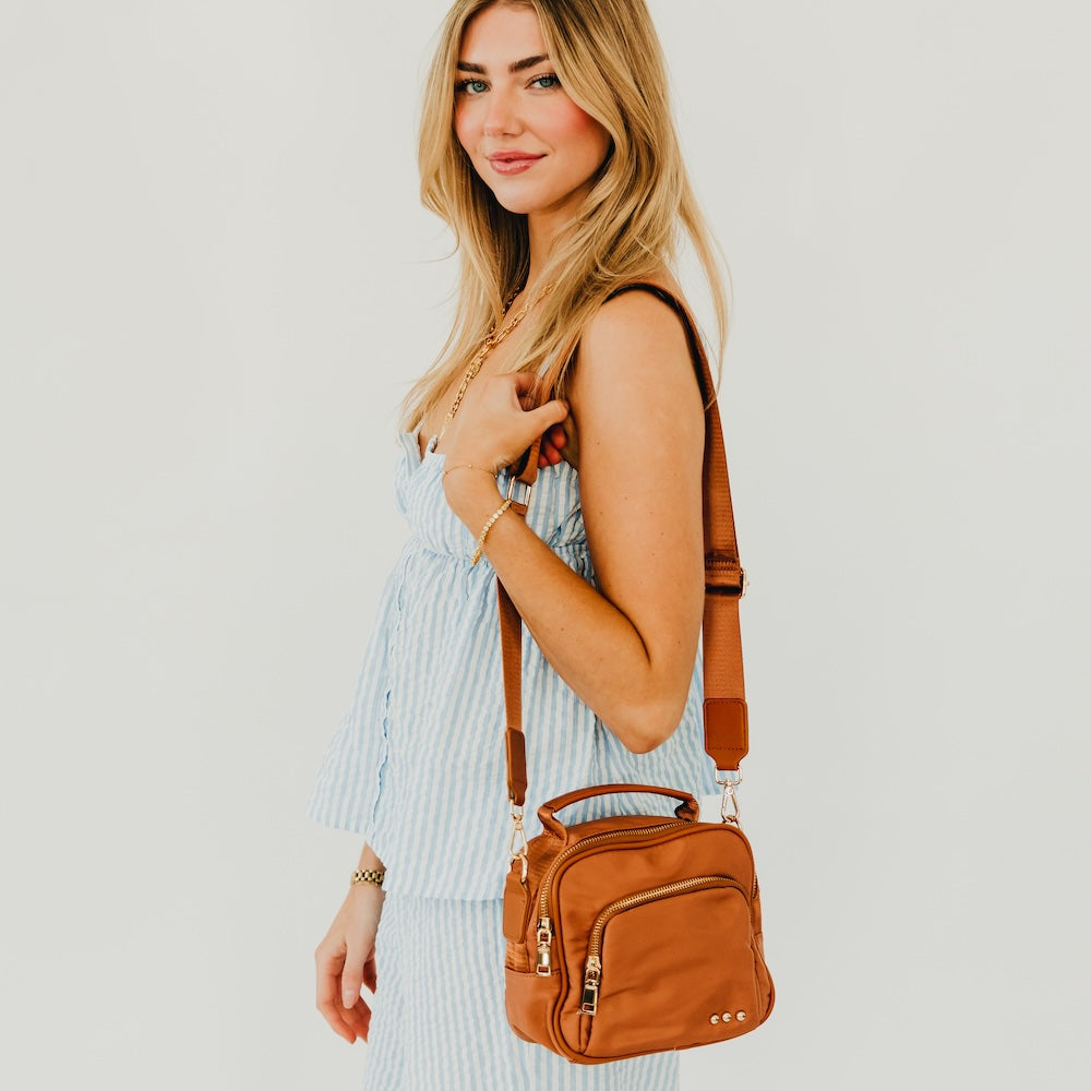 Brown nylon crossbody bag worn crossbody with adjustable strap
