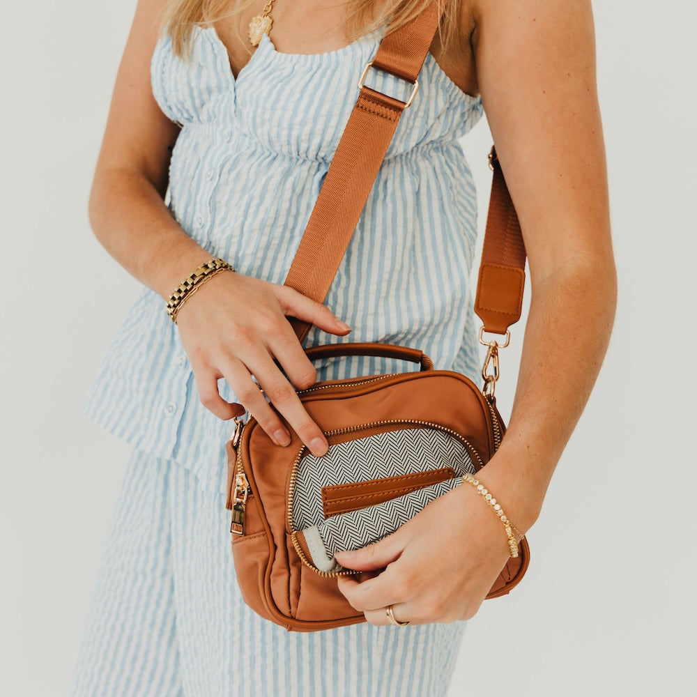 Brown nylon crossbody bag with top zip closure and front zip pocket
