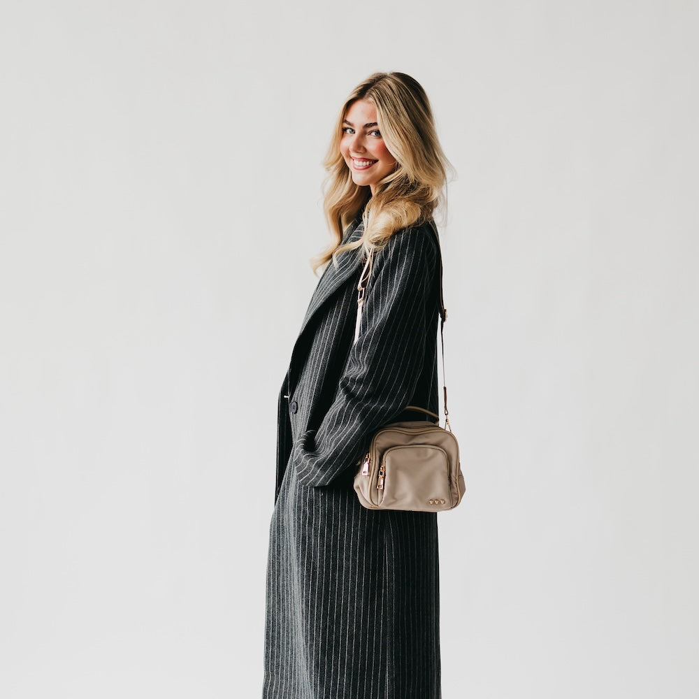 Taupe nylon crossbody bag worn crossbody with adjustable strap
