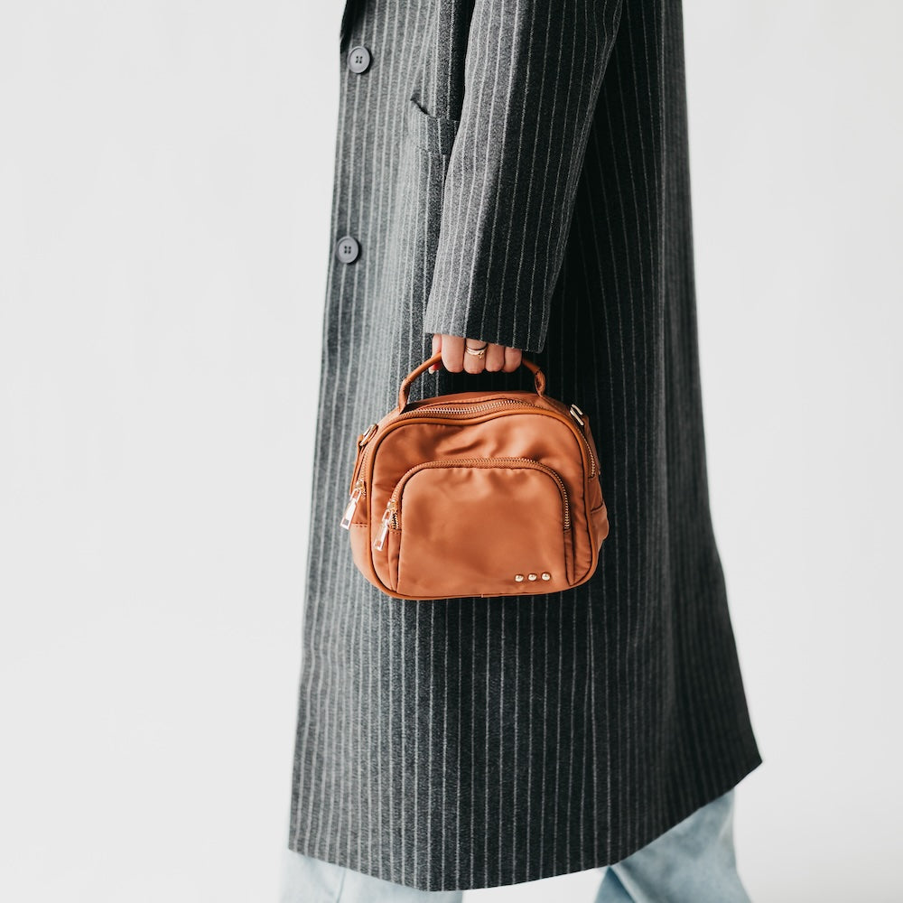 Brown nylon crossbody bag on arm with dual zippers and adjustable strap