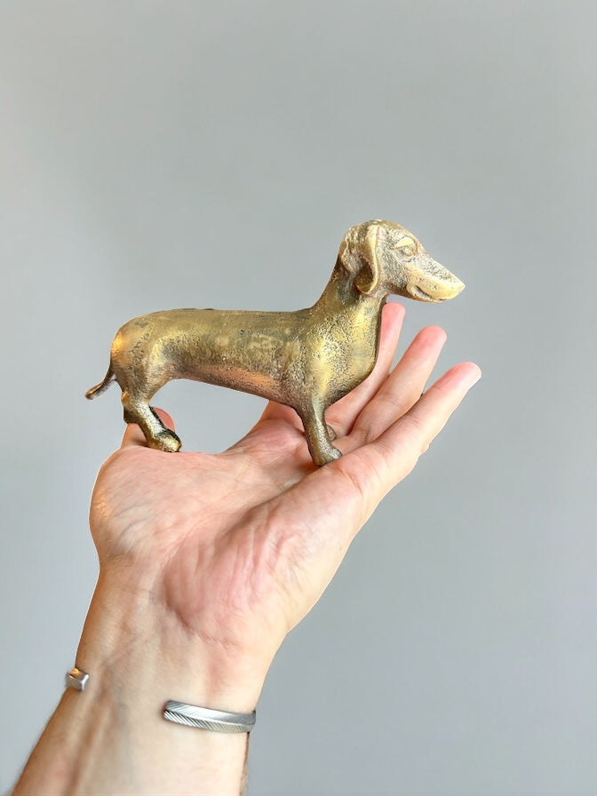 Antique brass dachshund figurine in cast aluminum, held in a hand for scale.