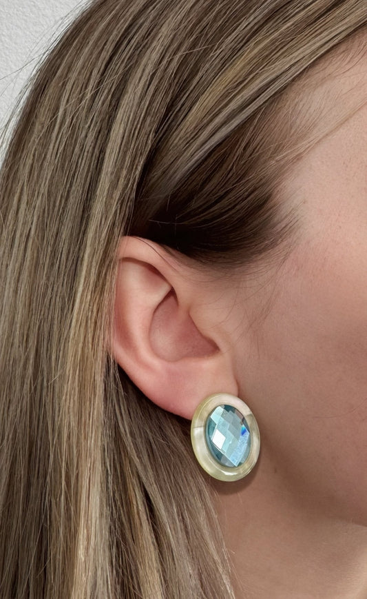 Oval blue faceted stud earring with iridescent stone in pale yellow-green setting