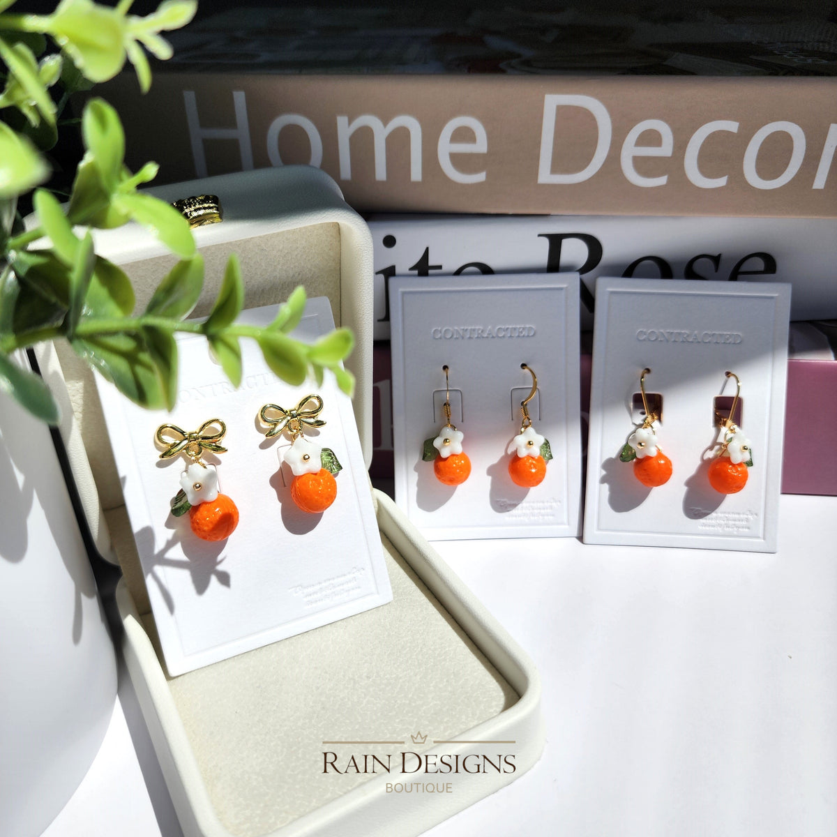 Orange fruit earrings with white flower and green leaf, gold bow-tie stud backs