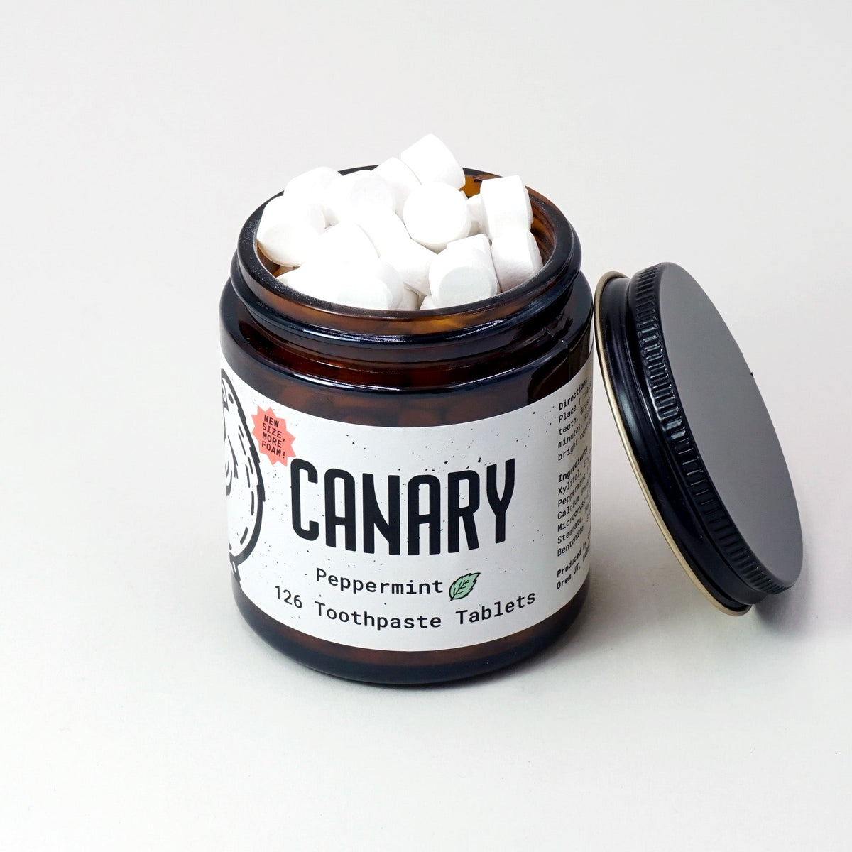Peppermint toothpaste tablets in an open amber jar