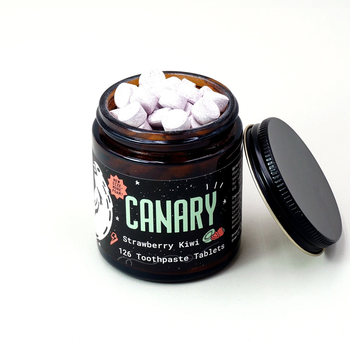 Open CANARY toothpaste tablet jar filled with tablets, with its lid beside it