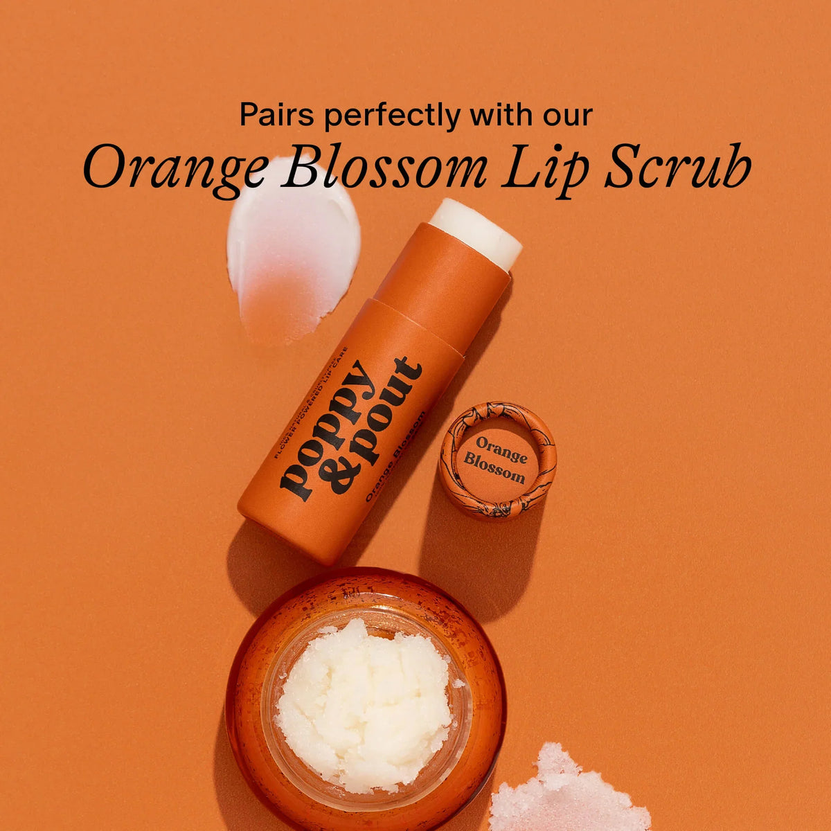 Orange blossom lip balm tube with open scrub jar and white scoop