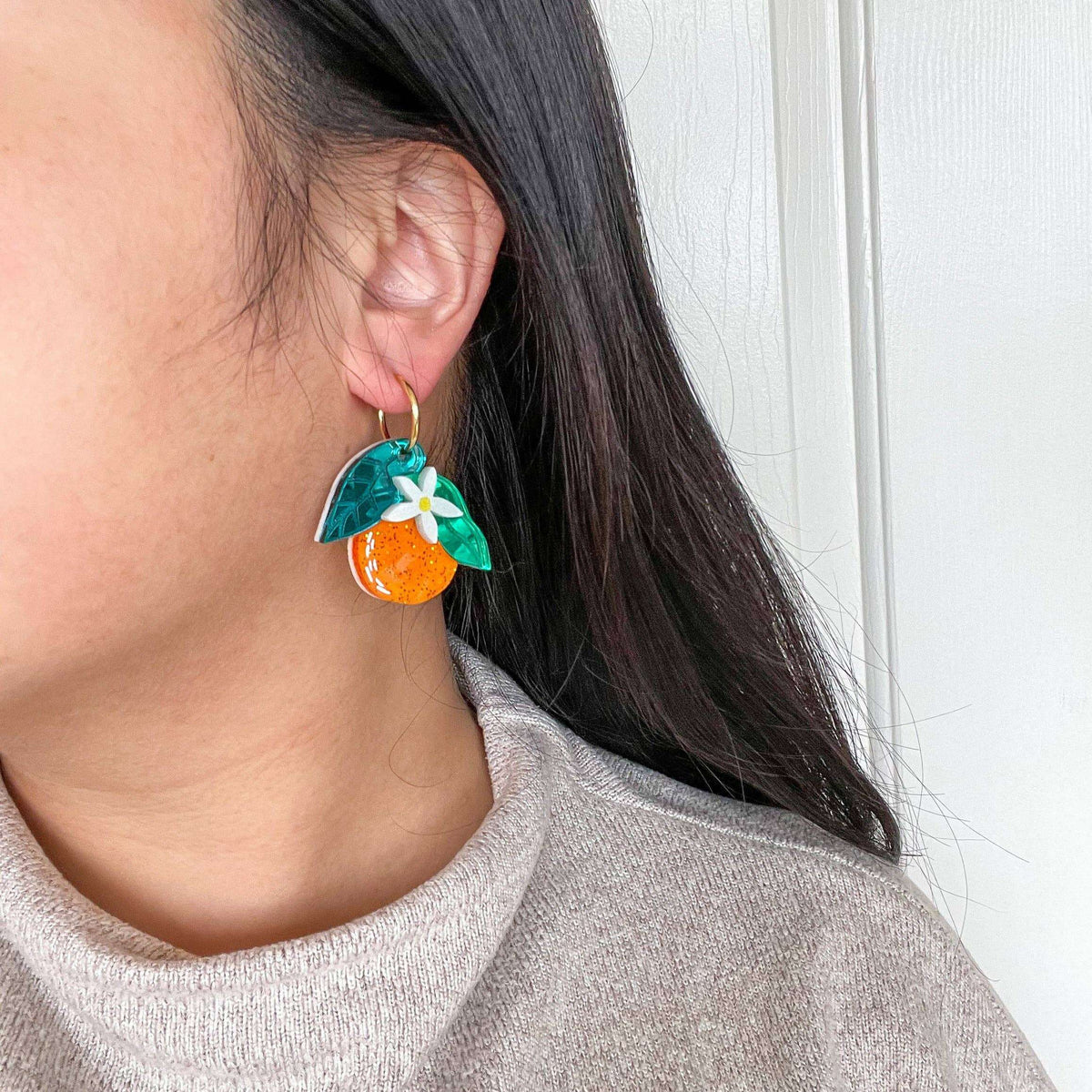 Orange and green dangle earrings with white flower charms and gold ear hooks