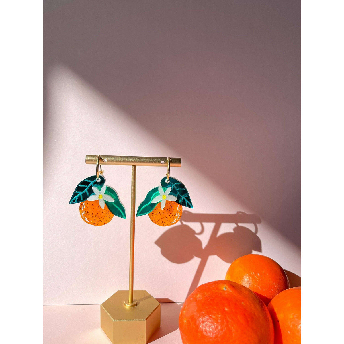 Orange fruit dangle earrings with green leaves and white blossoms on gold hooks